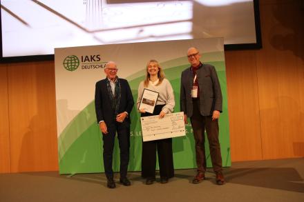 3 Leute schütteln Hände auf Bühne