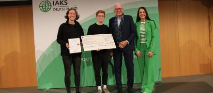 Studierenden lächeln mit Check und Urkunde in die Kamera