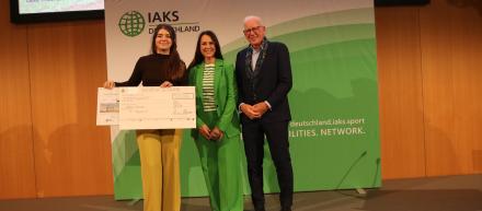 Studierenden lächeln mit Check und Urkunde in die Kamera