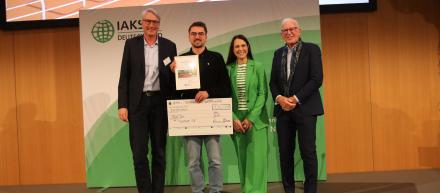 Studierenden lächeln mit Check und Urkunde in die Kamera