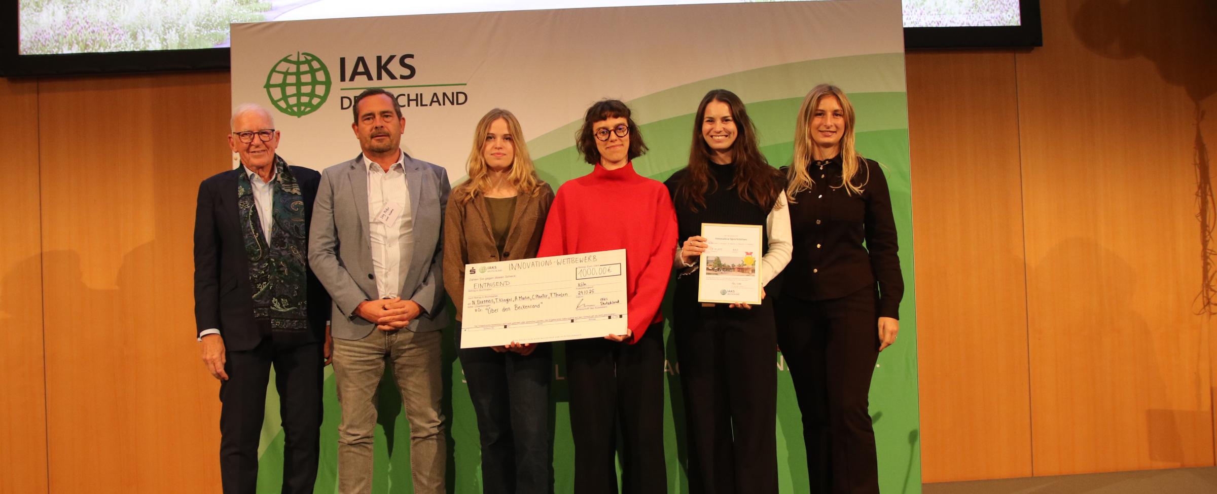 4 Menschen auf der Bühne, lächeln in die Kamer