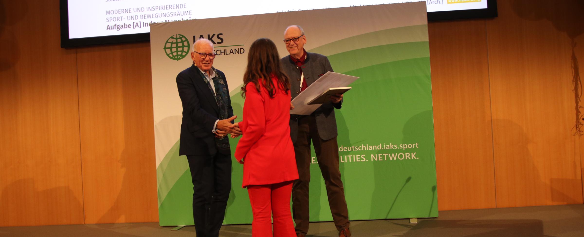 3 Leute schütteln Hände auf Bühne