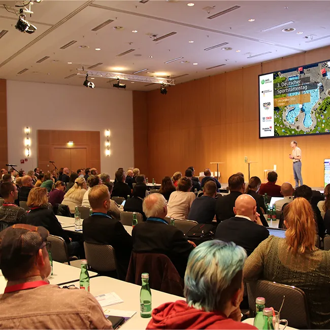 menschen im saal schauen auf bühne