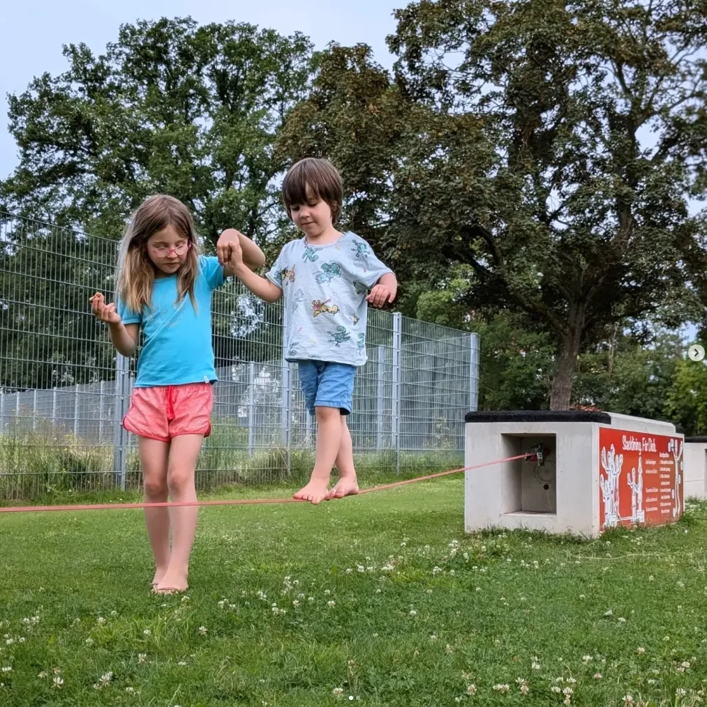 zwei kinder auf einer Slackline im Freien
