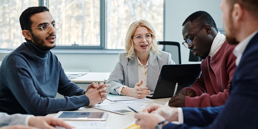 mehrere Anzugträger diskutieren freundlich am Tisch