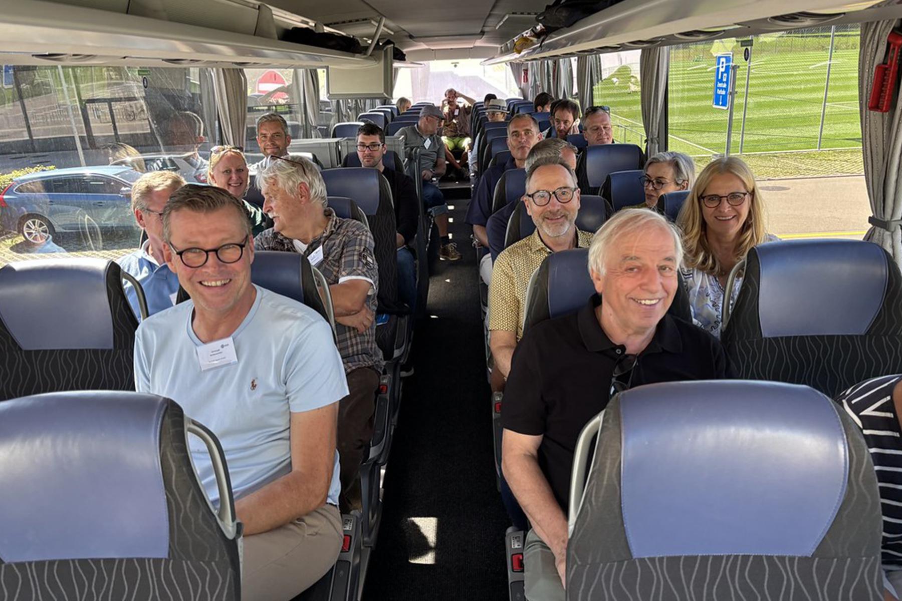 Menschen sitzen im Reisebus und lächeln in die Kamera