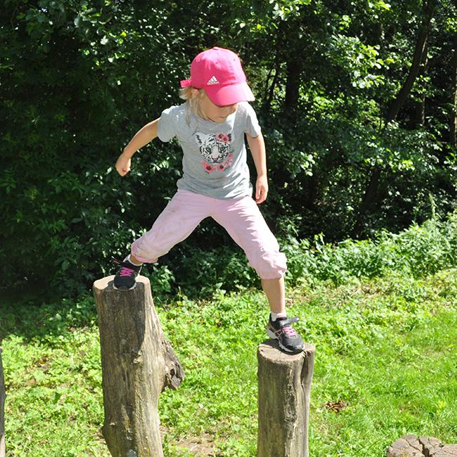 Girl standing on two tree trunks