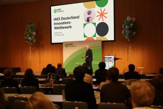 IAKS Innovations-Wettbewerb Robin Kähler steht auf der Bühne vor Publikum